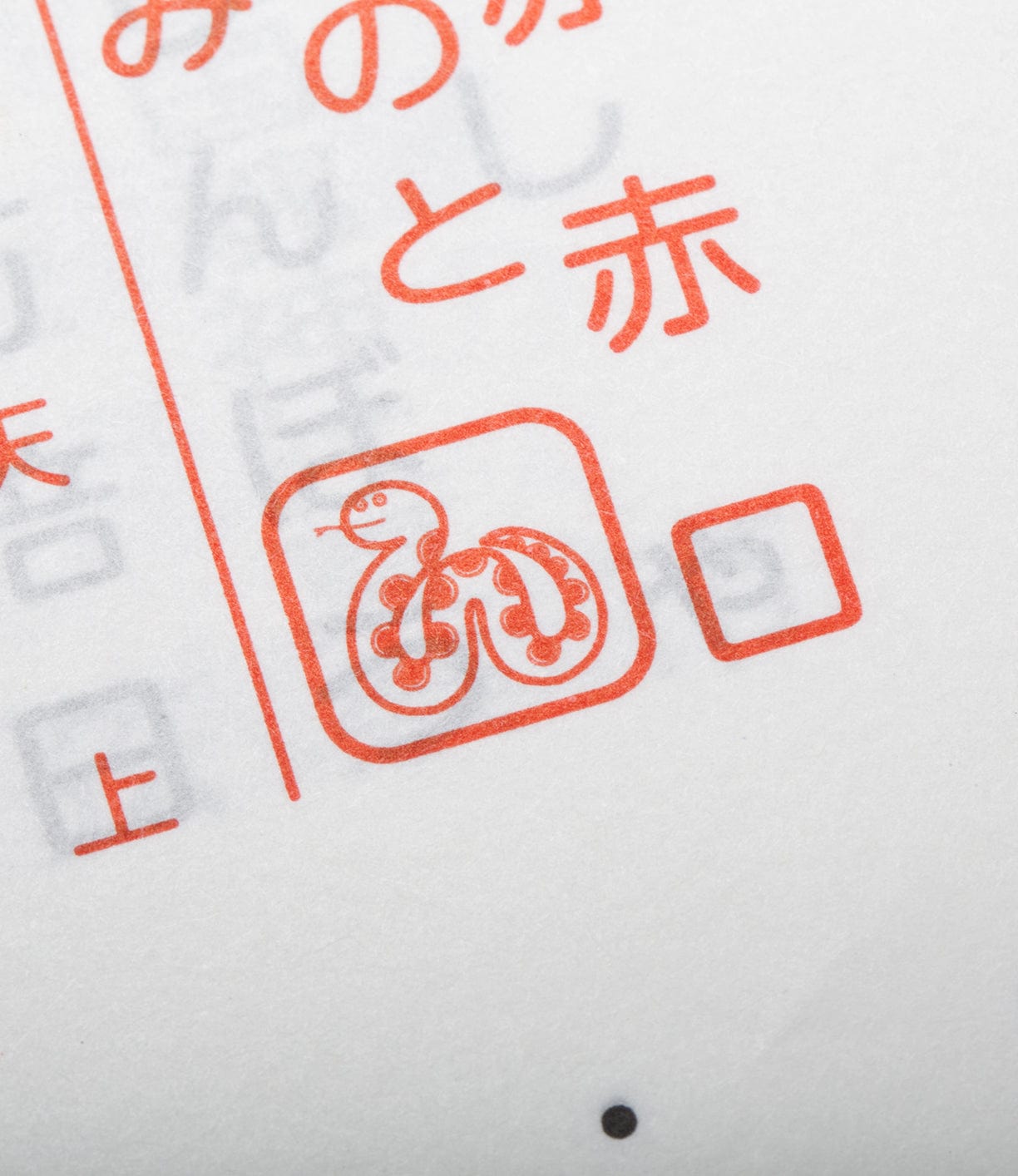 Close-up of a red stamp featuring a snake coiled into a spiral shape, surrounded by Japanese text on a white paper.