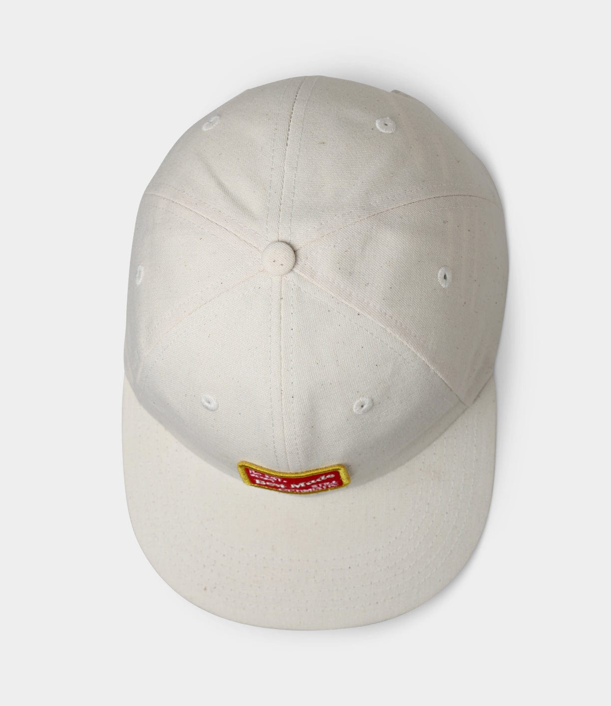 A white baseball cap with a yellow and red rectangular patch on the back, seen from above, against a white background.