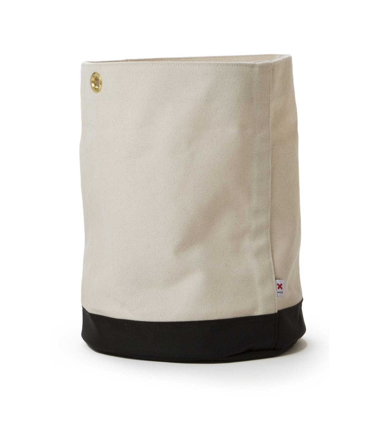 A beige canvas bag with a black bottom, featuring a button detail near the top and a small fabric tag on the lower right side.