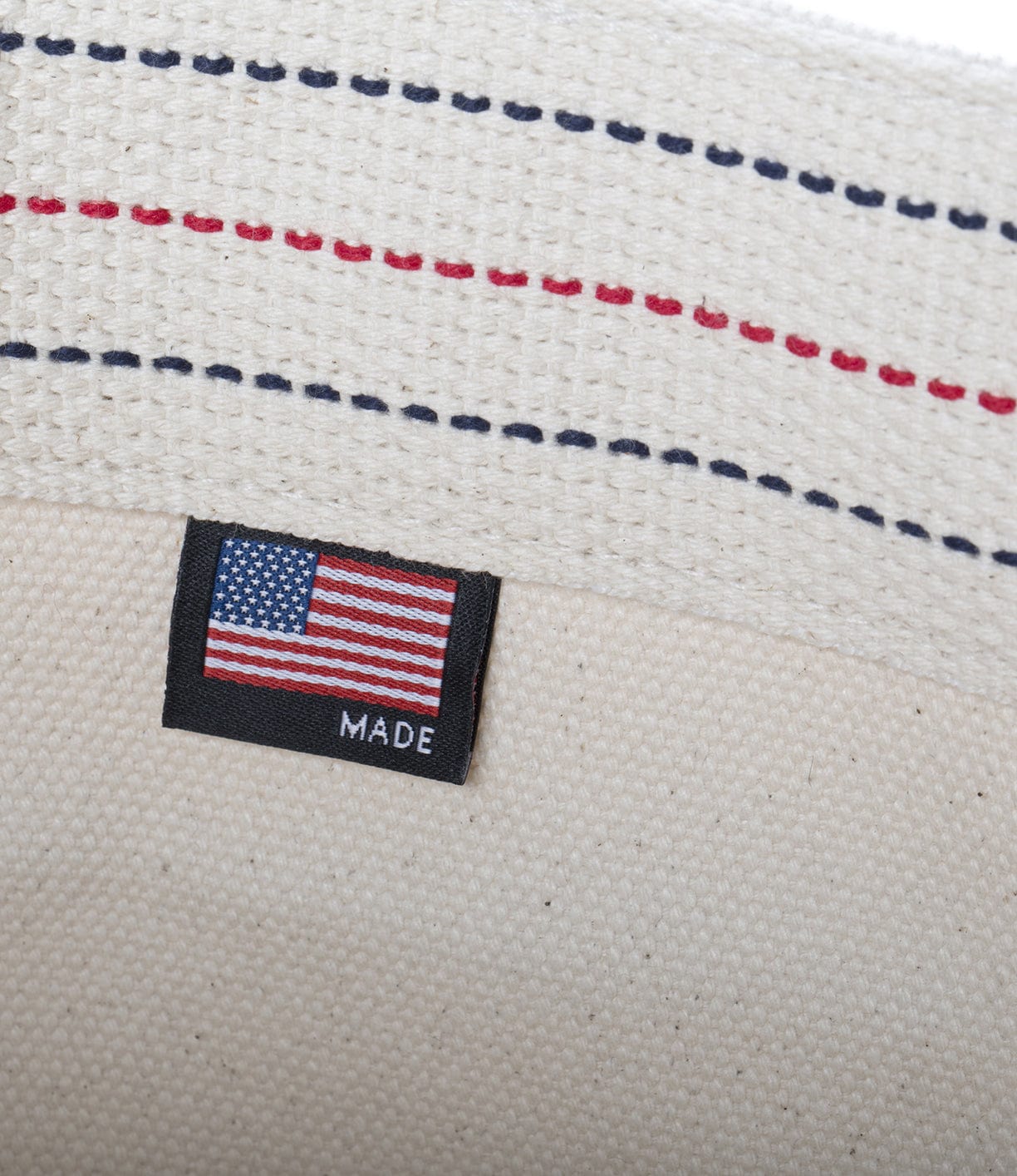 A fabric label with an American flag and the word MADE sewn onto beige fabric with red and blue stitching.