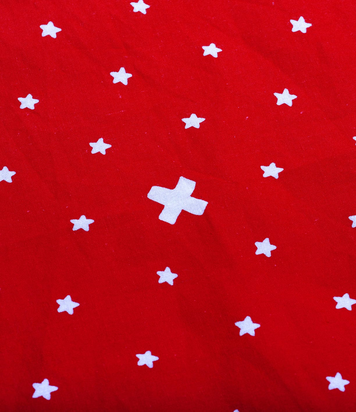 Red fabric with white stars and a single white cross in the center.