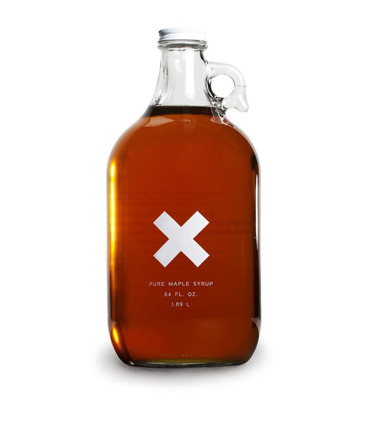 A large glass bottle with a handle, containing 64 fl. oz. (1.89 L) of pure maple syrup, with a white 'X' on the front label.