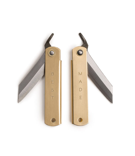 Two brass utility knives with open blades. The handles are engraved with the words BEST on one knife and MADE on the other.