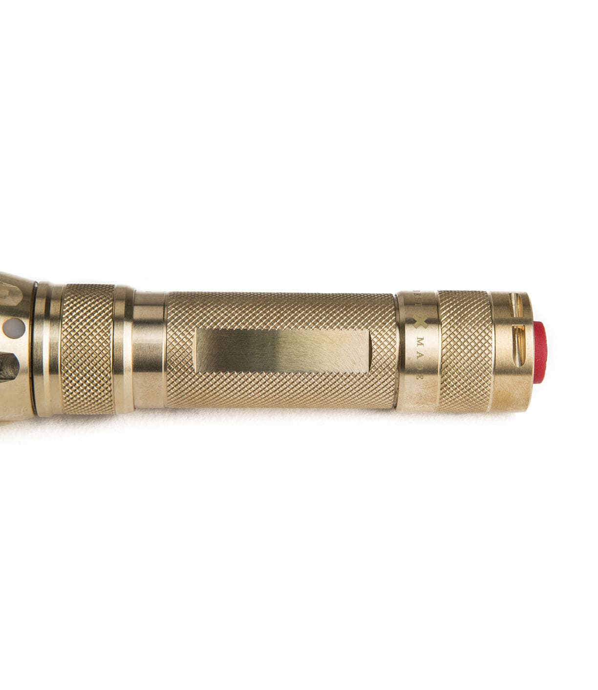 A brass flashlight with a textured grip and a red button on the end.