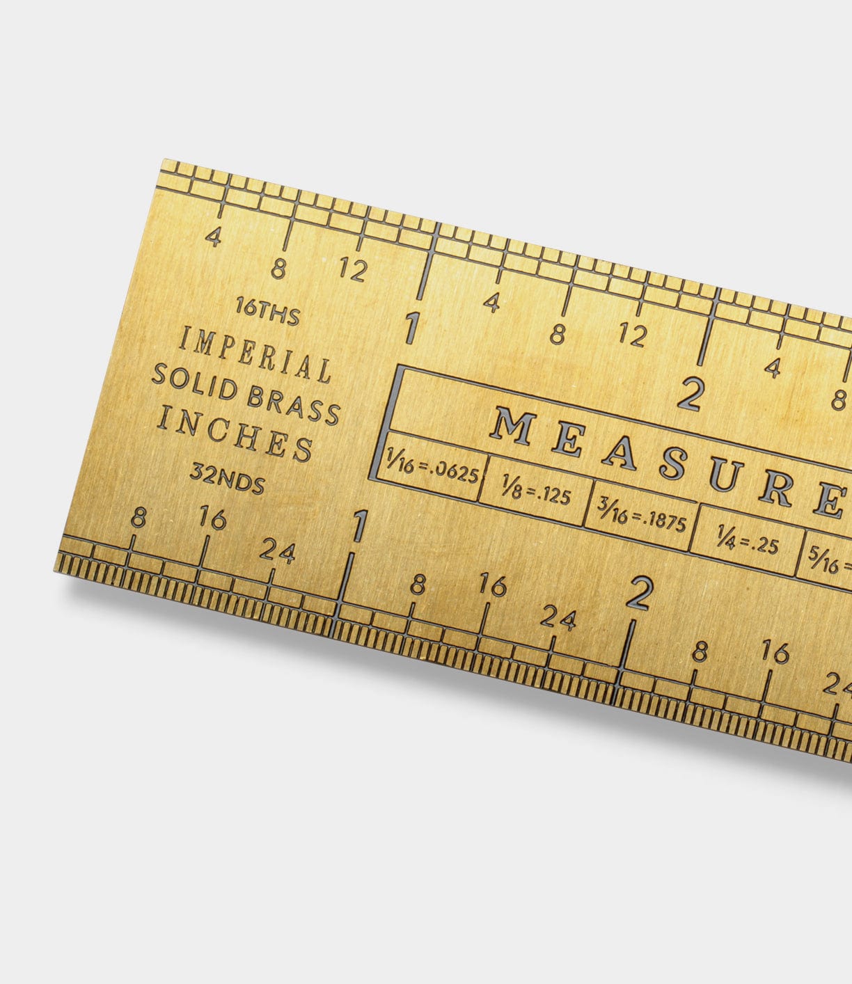 Close-up of a brass ruler with inch and fractional measurements. The text reads, 16THS IMPERIAL SOLID BRASS INCHES 32NDS.