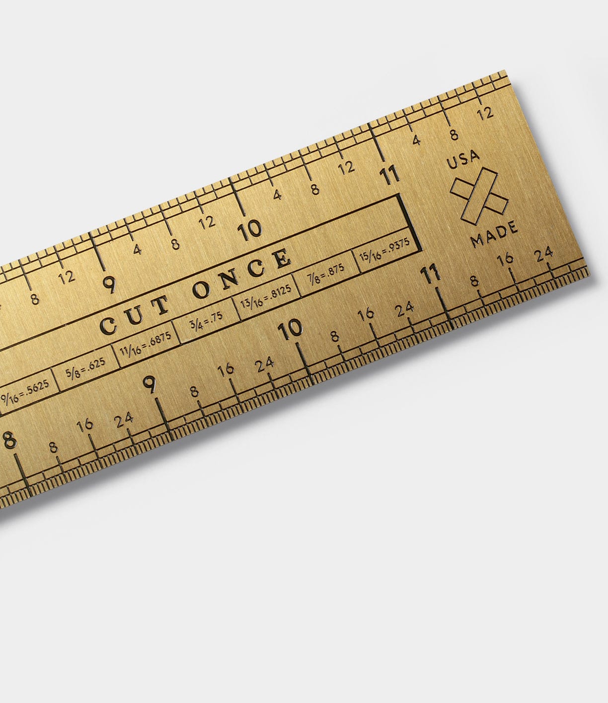 A gold-colored metal ruler with measurements in inches and centimeters, detailed markings, and the phrase CUT ONCE engraved. It also has USA MADE with a small cross icon.