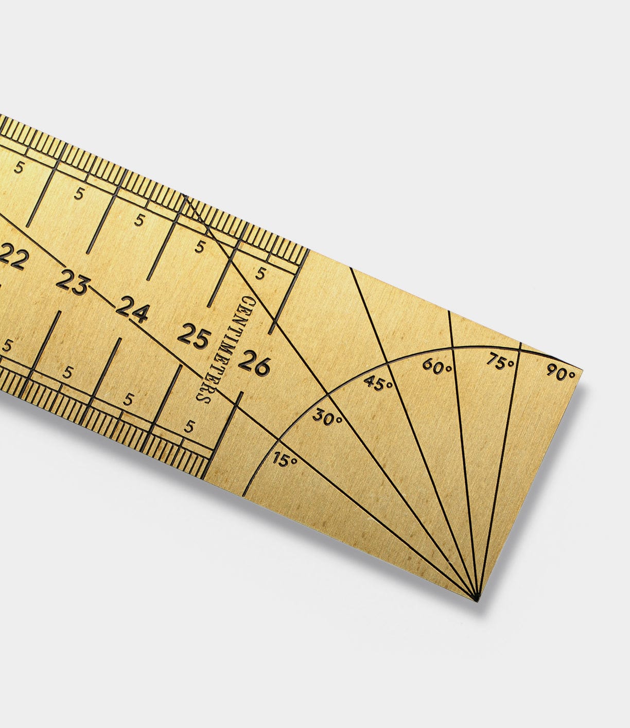 A close-up of a gold-colored protractor ruler showing measurements in centimeters from 21 to 29, along with marked angles from 0¬∞ to 90¬∞.