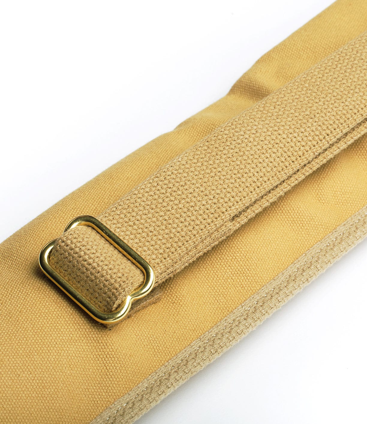 Close-up of a beige fabric strap with a gold-colored metal buckle. The strap appears to be part of a larger item, possibly a bag or piece of luggage.