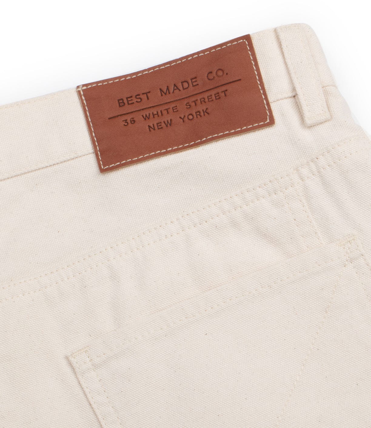 Close-up of beige pants with a brown leather label sewn on the waistband. The label reads Best Made Co., 36 White Street, New York.