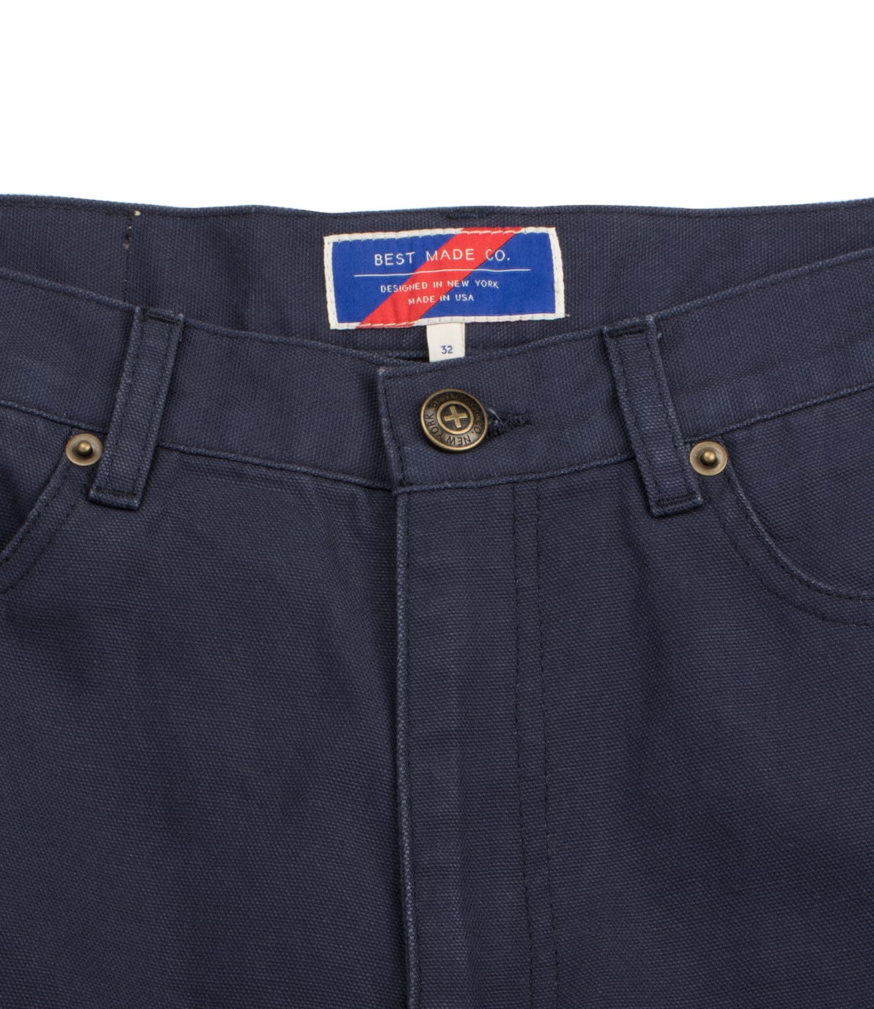 Close-up image of navy blue pants with a front button closure and belt loops. The label reads Best Made Co. Designed in New York, Made in USA. The size is 32.