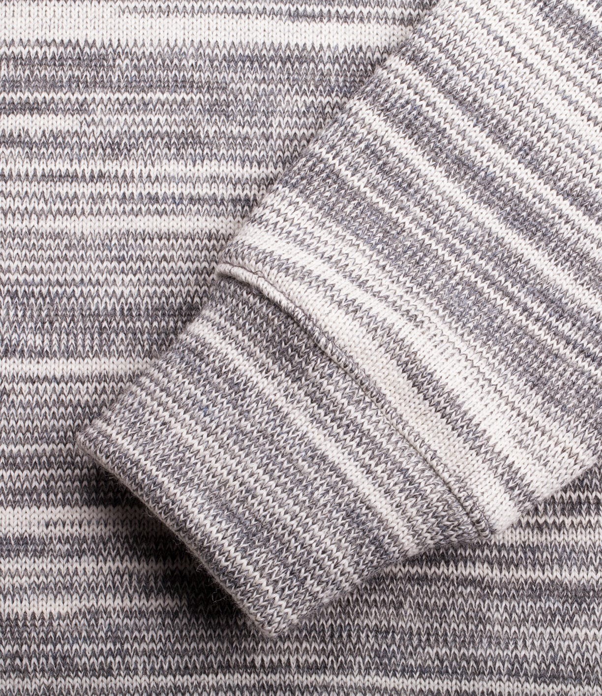 Close-up of a gray and white striped knitted fabric with a sleeve cuff in the foreground.