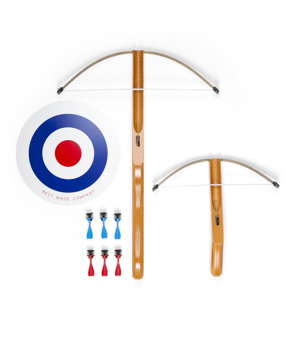 Two wooden crossbows, one large and one small, are displayed alongside a round target and eight projectile darts, four in red and four in blue.