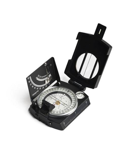 A black Brunton compass with a sighting mirror and level vial, showing detailed incremental markings and dials on a white background. The lid is open revealing the compass face.