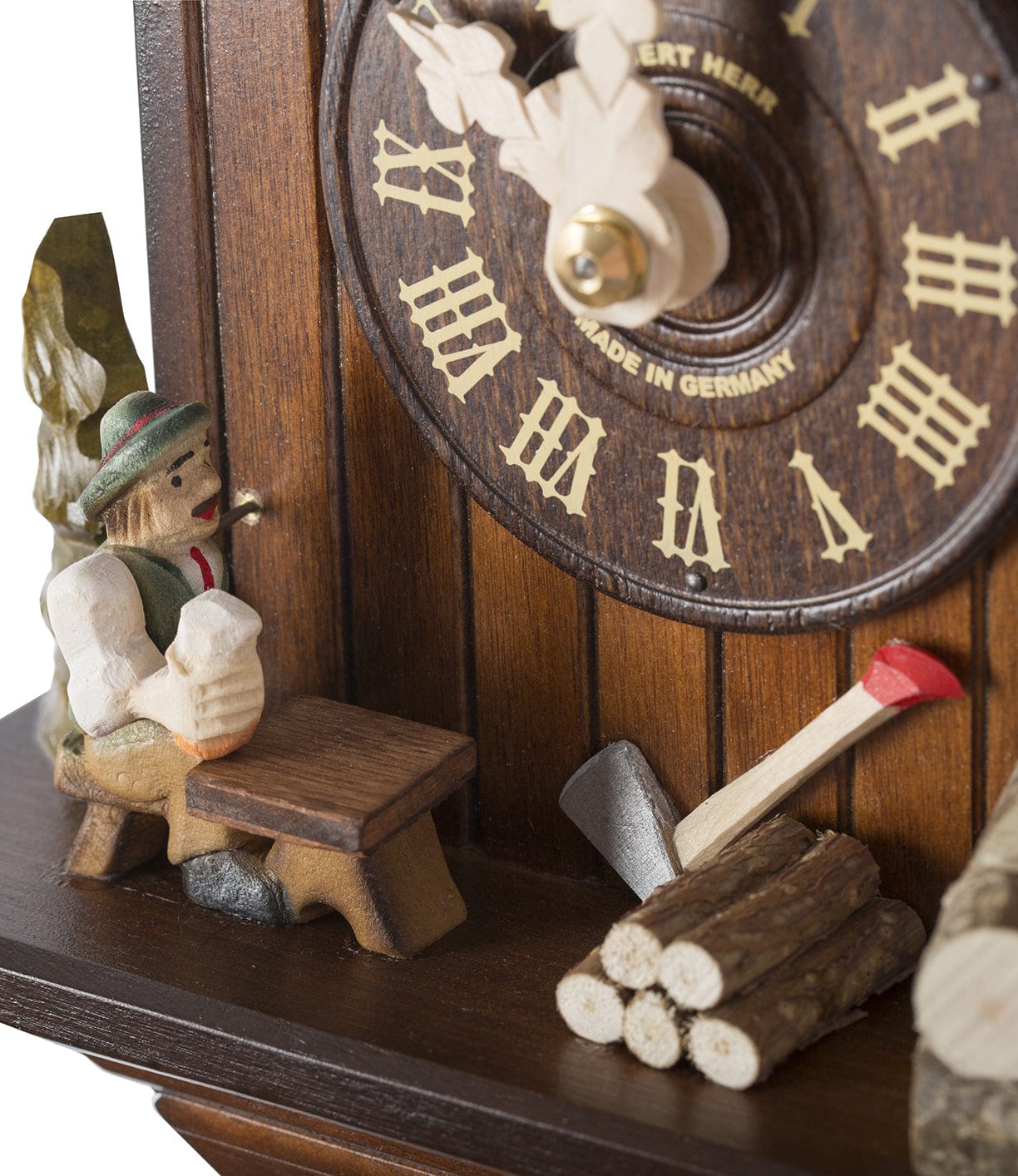 Close-up of a traditional German cuckoo clock showing a carved figure holding a beer mug, a wooden bench, and an axe with logs underneath the clock face.