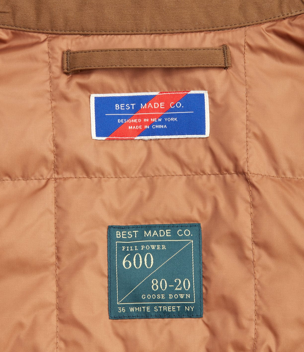 Close-up of a jacket's interior labels. The top label reads Best Made Co. Designed in New York, Made in China. The bottom label details 600 fill power, 80-20 goose down, 36 White Street, NY.