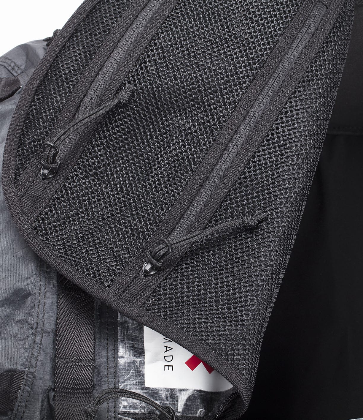 Close-up of a black backpack with open zippers revealing mesh pockets and a Made in Vietnam label inside.