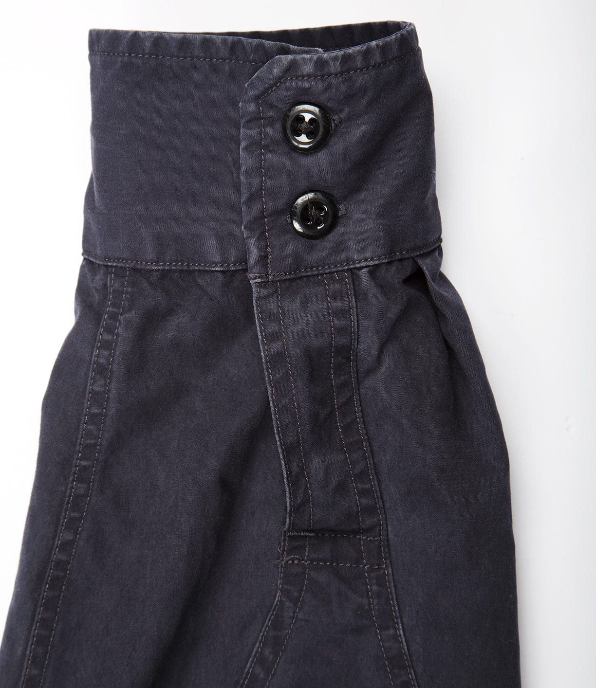 Close-up view of a dark grey garment with a high waistband featuring two black buttons and visible stitching.