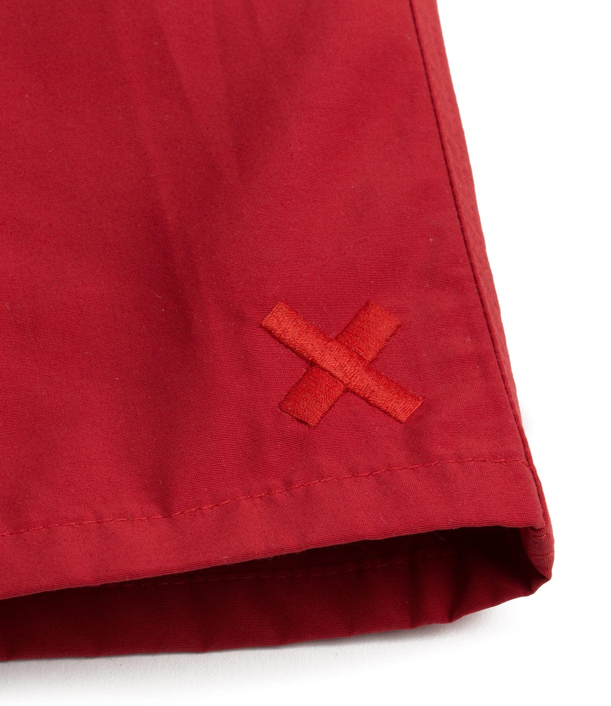 Close-up of a red fabric with a stitched red 'X' symbol at the edge.