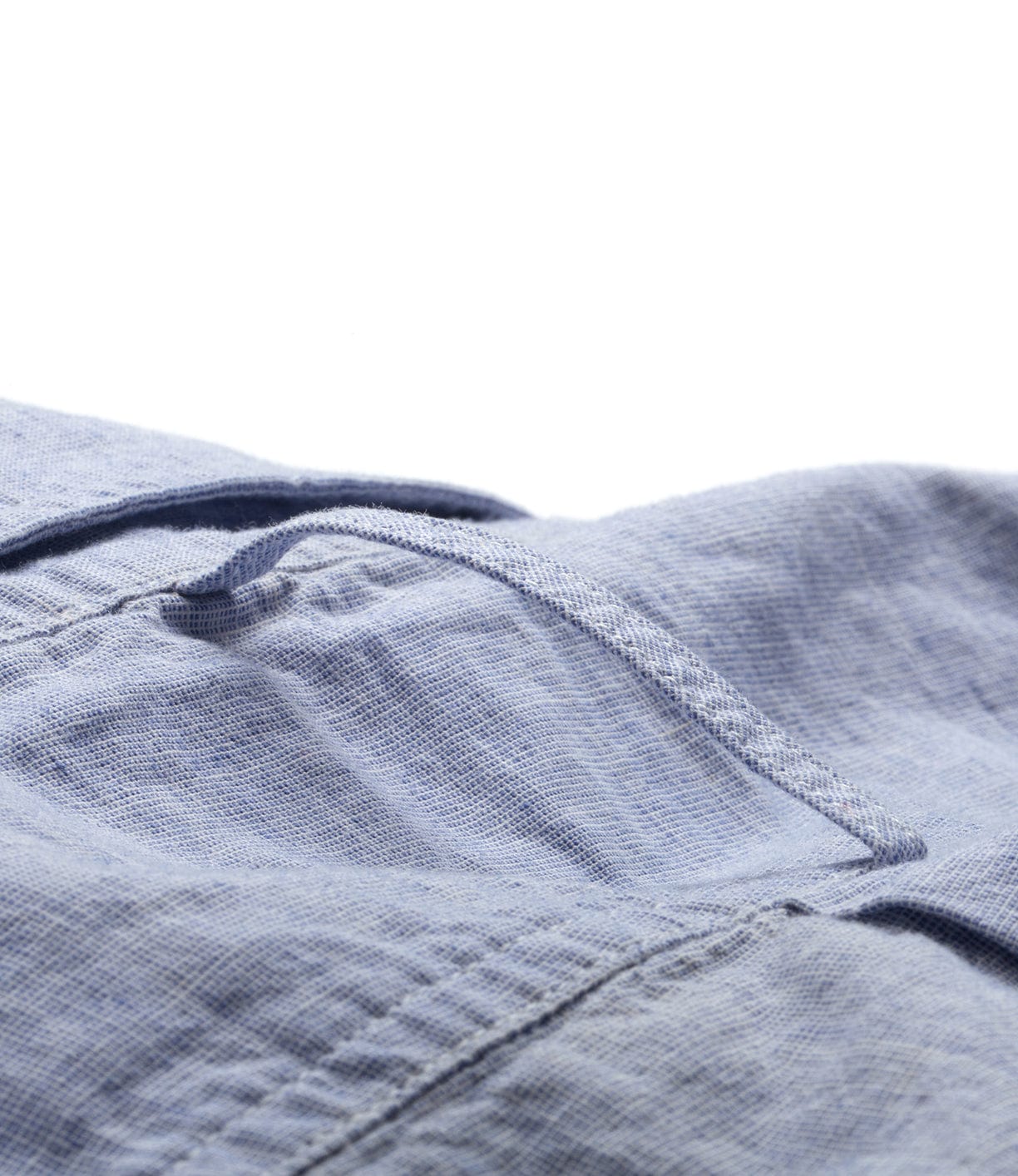 Close-up image of a blue fabric with a folded seam and a visible wrinkle line, highlighting its texture and stitch details.