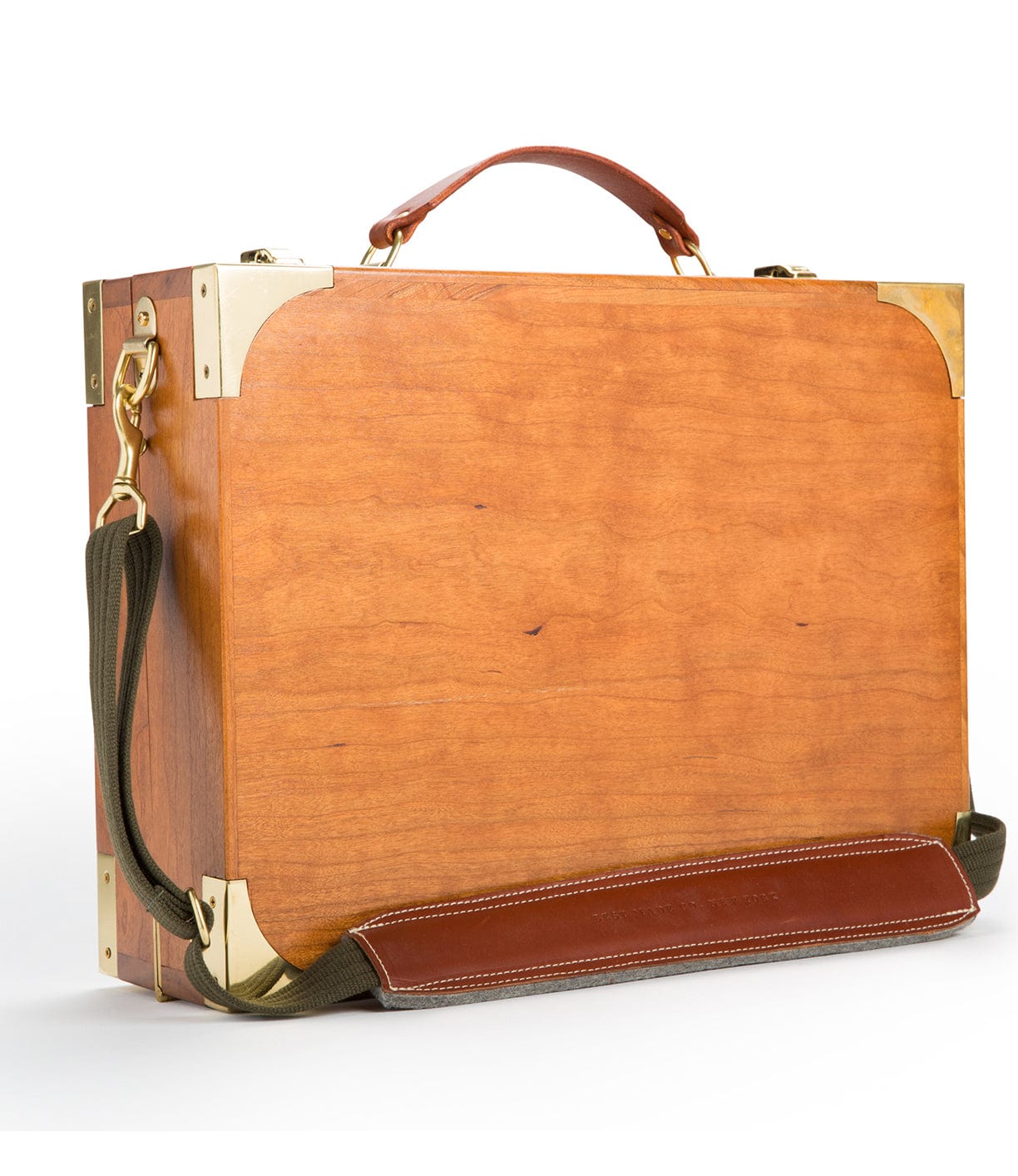 A rectangular wooden briefcase with brass corners, a brown leather handle, and a green shoulder strap against a white background.