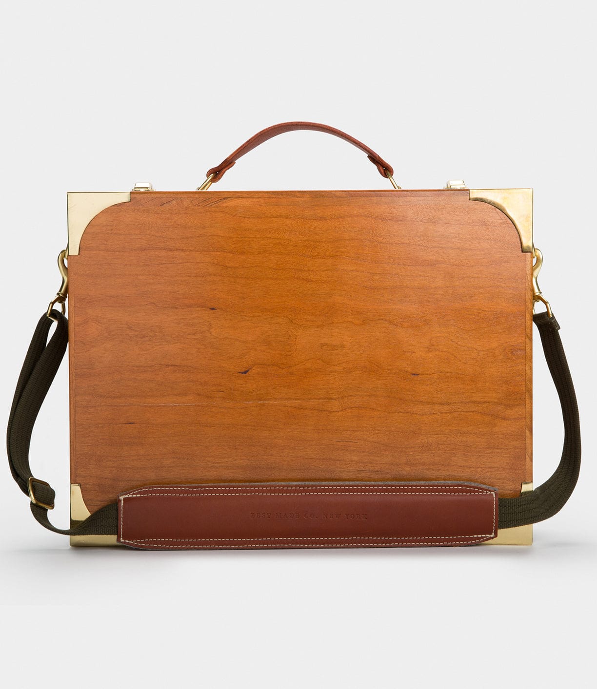 A wooden briefcase with brass accents, a brown leather handle, and an adjustable green strap.