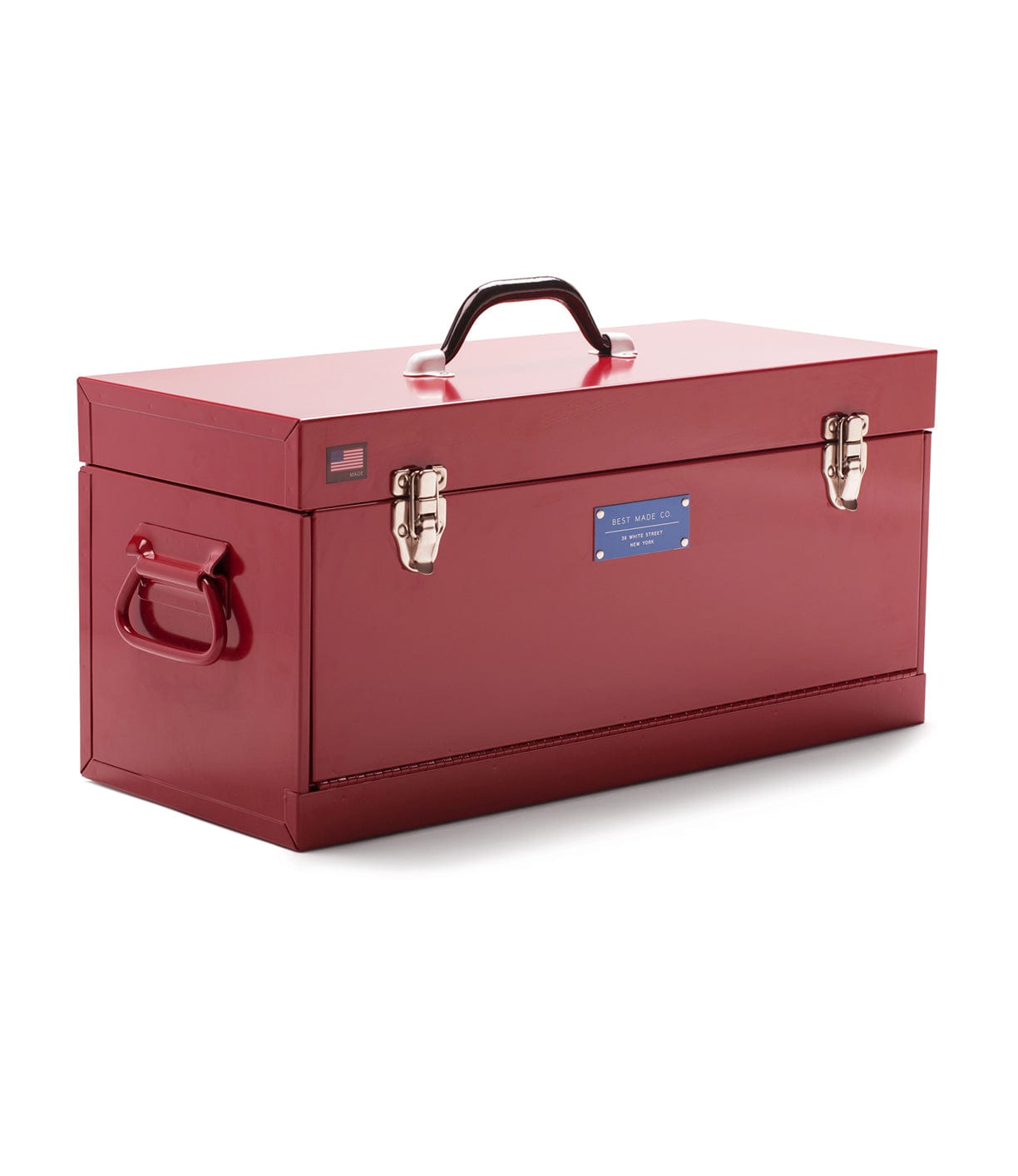 A closed, rectangular, red metal toolbox with a black handle on top, two silver latches in front, and a small American flag and blue label visible.