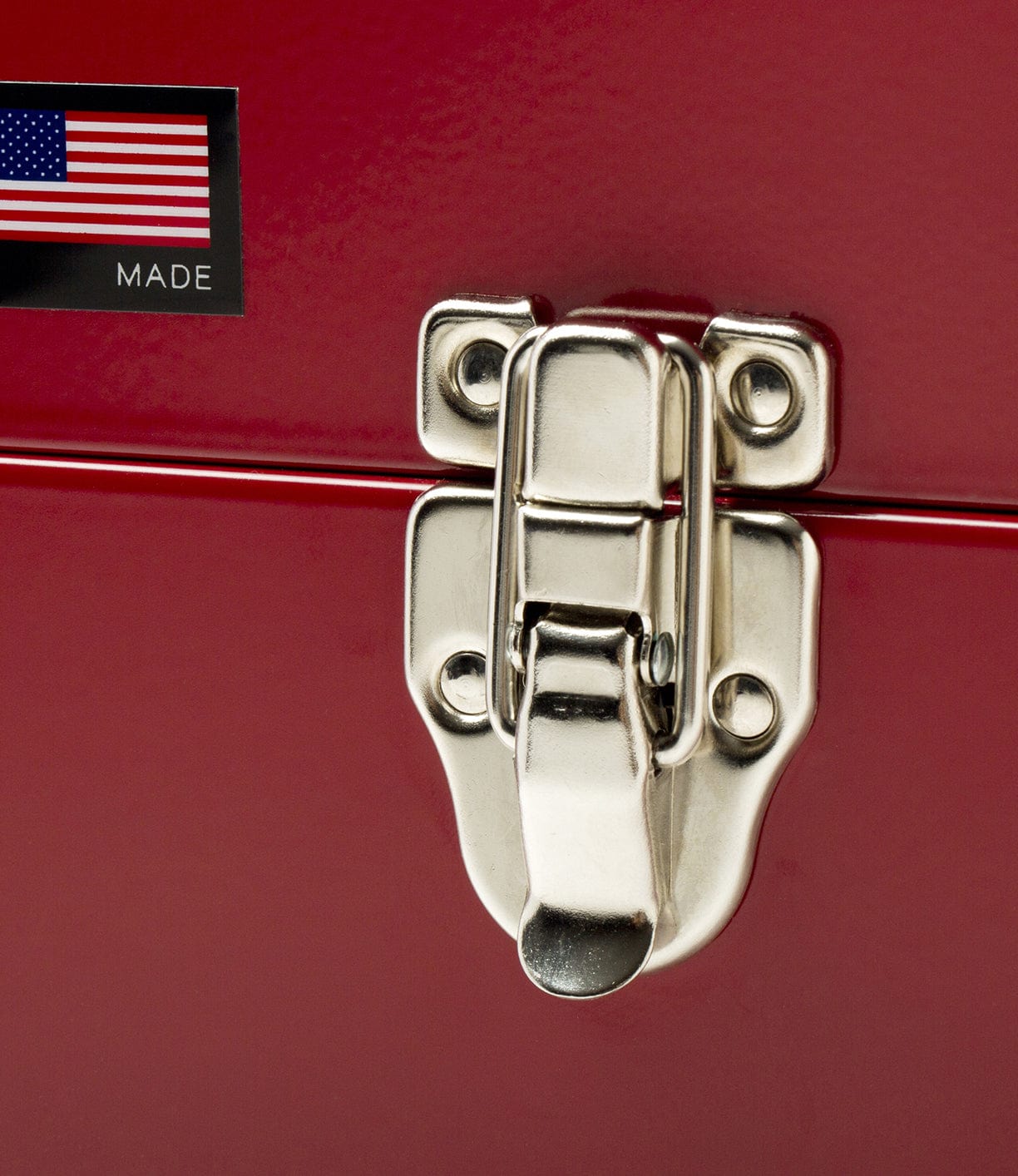 Close-up of a latch on a red metal box, featuring an American flag sticker labeled MADE.