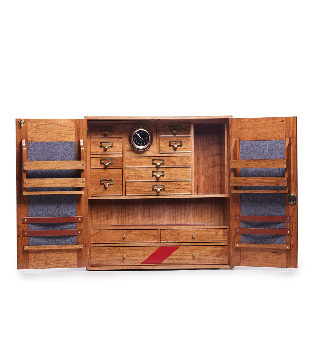 A wooden cabinet with open doors featuring several drawers, compartments, and a small round clock in the center. The interior includes felt-lined sections and a red diagonal stripe on one drawer.