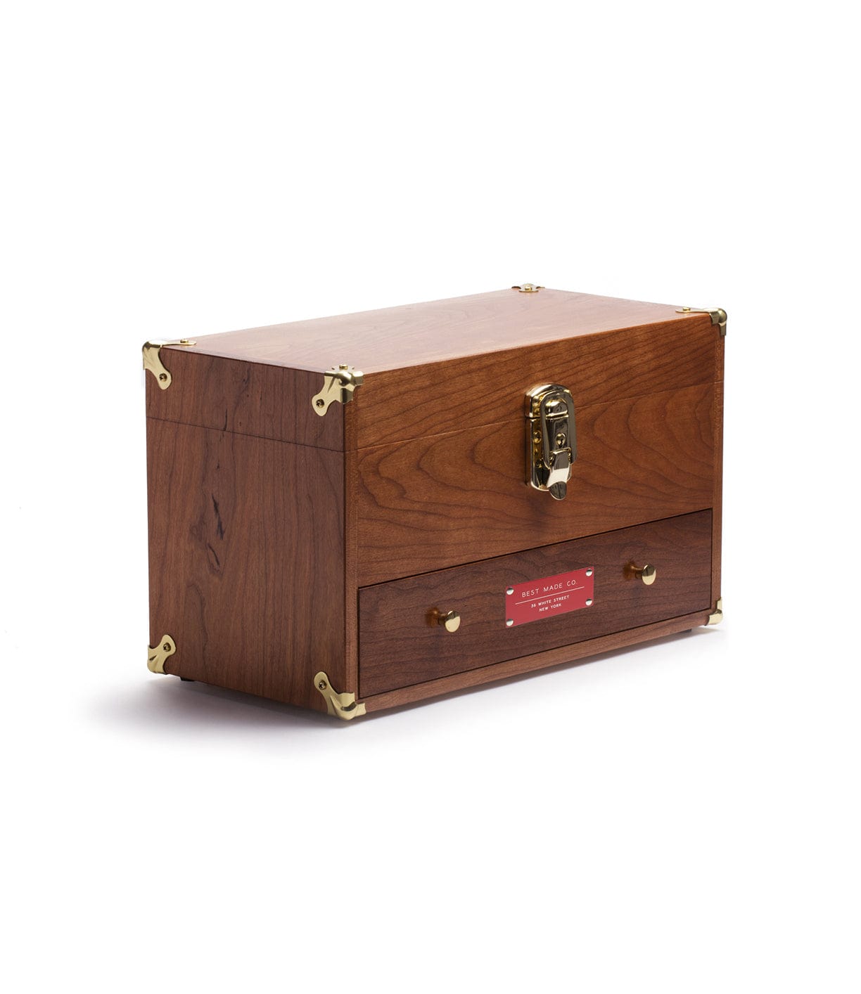 A wooden storage chest with a brass latch and corner accents, featuring a red label on a bottom drawer.