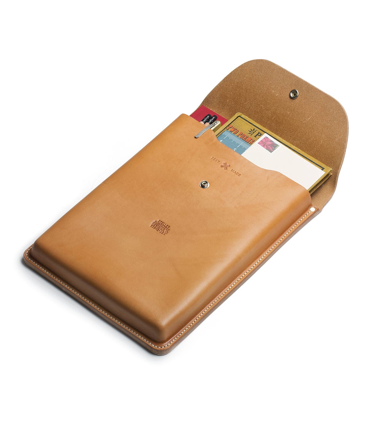 A tan leather folder with a snap closure, partially open to reveal various stationery items including a notebook, a calendar, and some pens.