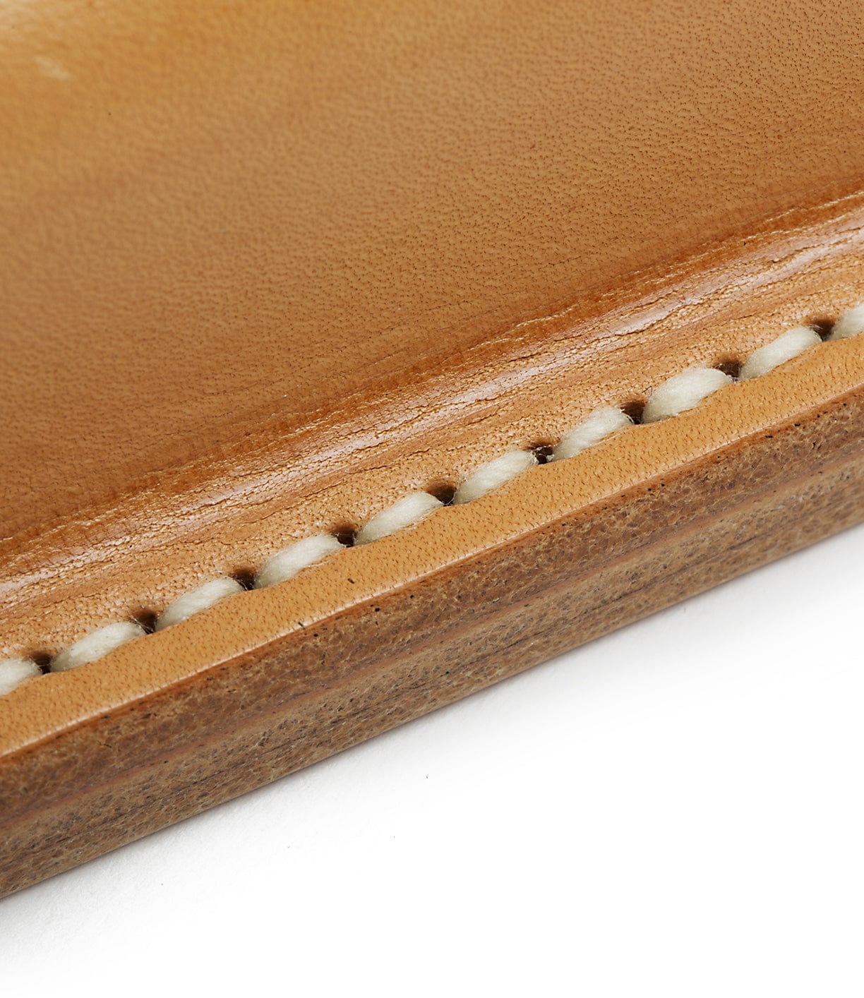 Close-up of a leather stitching detail in beige and brown tones, showing precise thread work and a smooth finish.