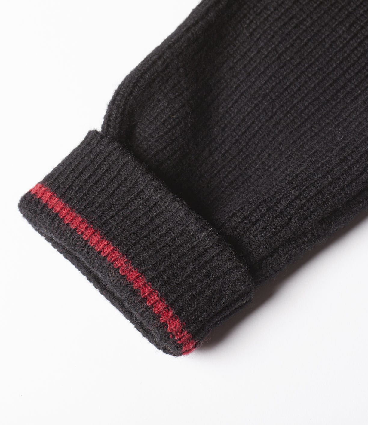 Close-up of a black knitted sleeve cuff with two red stripes near the edge, photographed on a white background.