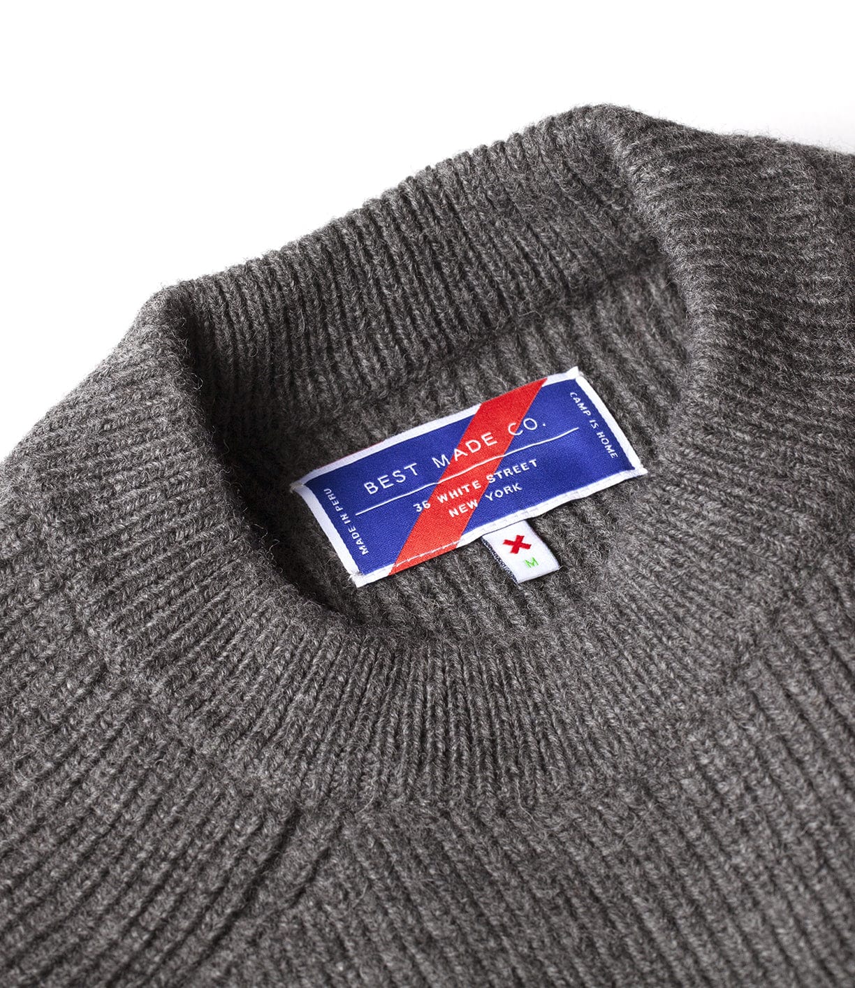 Close-up of a grey ribbed sweater's collar with a Best Made Co. label showing the brand's address in New York.