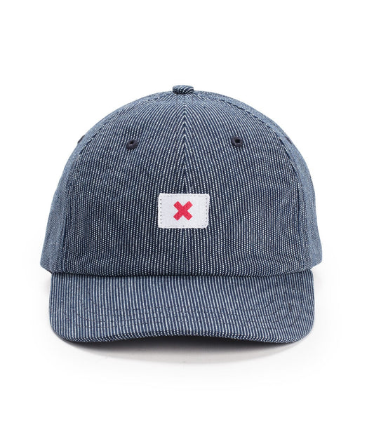 A blue striped baseball cap with a small rectangular patch displaying a red X on the front.