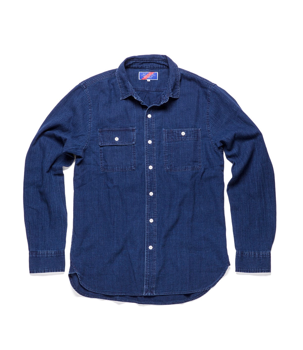 Denim long-sleeve shirt with button-down front, two chest pockets, and a rounded hem.