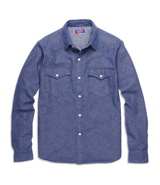 A blue long-sleeve denim shirt with a collar and button-up front, featuring two chest pockets with buttoned flaps.