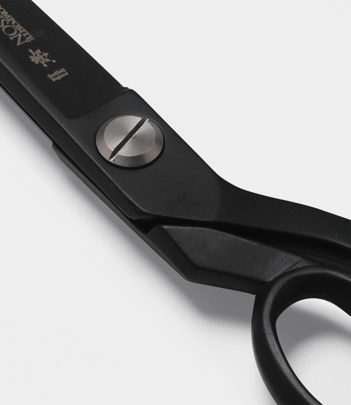 Close-up of a black pair of scissors with a visible pivot screw on a white background.