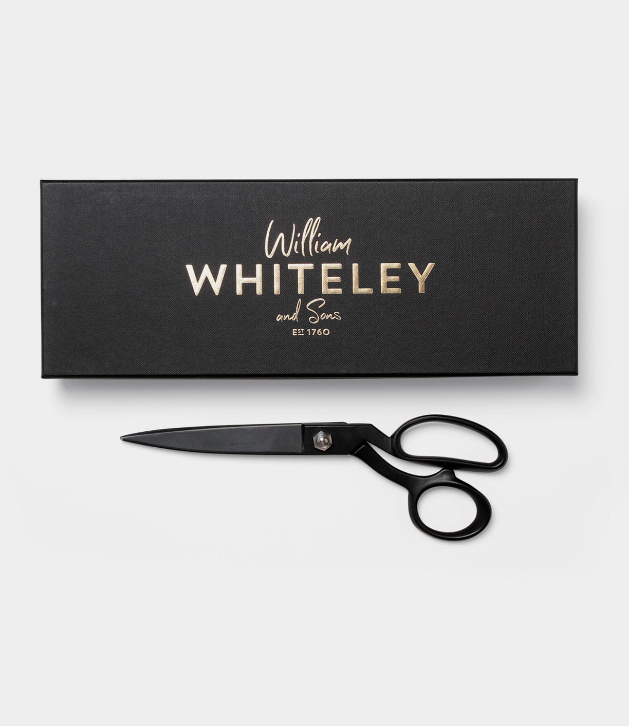 A pair of black scissors is placed next to a black box that has the text William Whiteley and Sons Est 1760 in gold lettering on it.