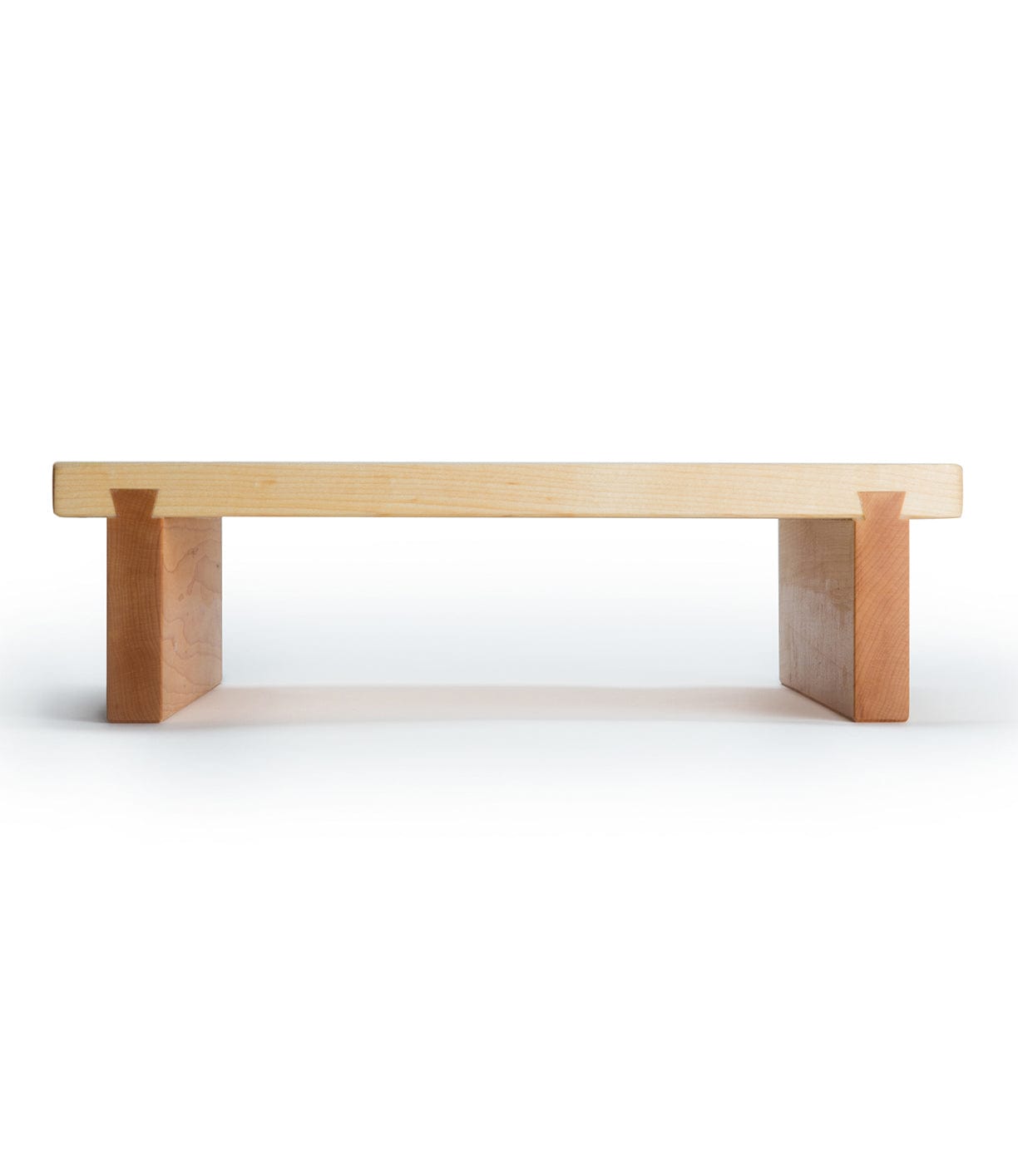 A simple wooden bench with a flat seat and two rectangular legs, crafted from light-colored wood.