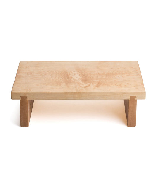 A rectangular wooden table with a light wood surface and sturdy, short legs.