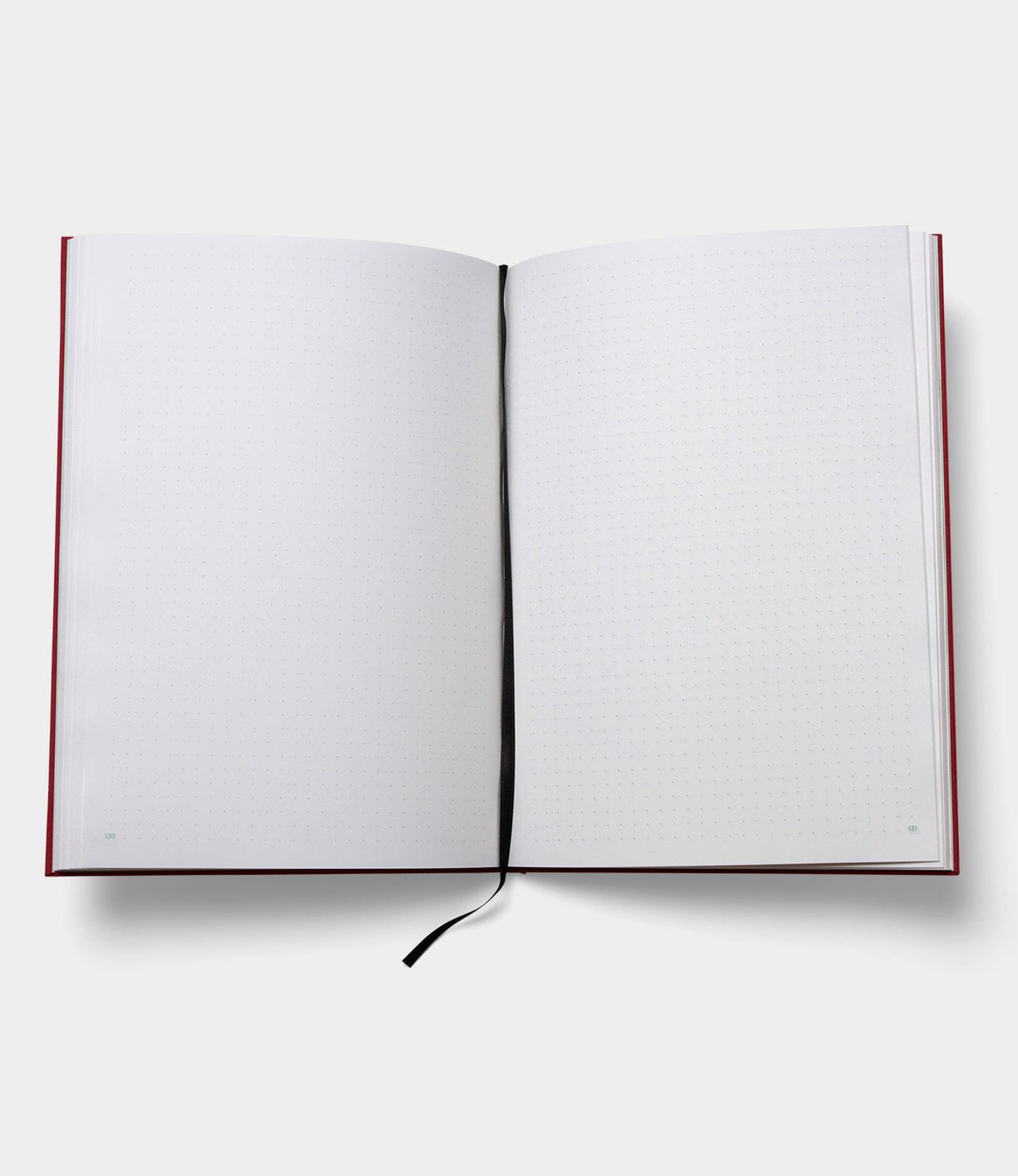 Open notebook with blank, dotted pages and a black ribbon bookmark placed in the center fold.