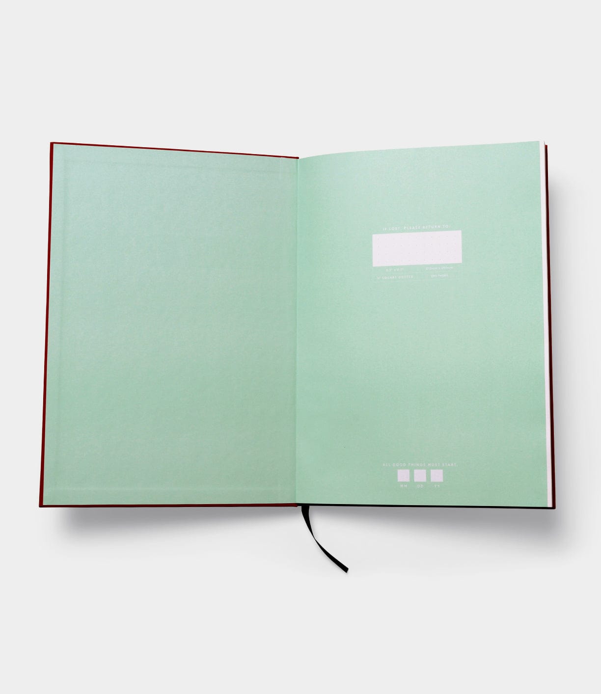 An open book showing a blank mint-green endpaper with a black ribbon bookmark centered at the bottom. The endpaper contains small white text and a white rectangular box near the top.