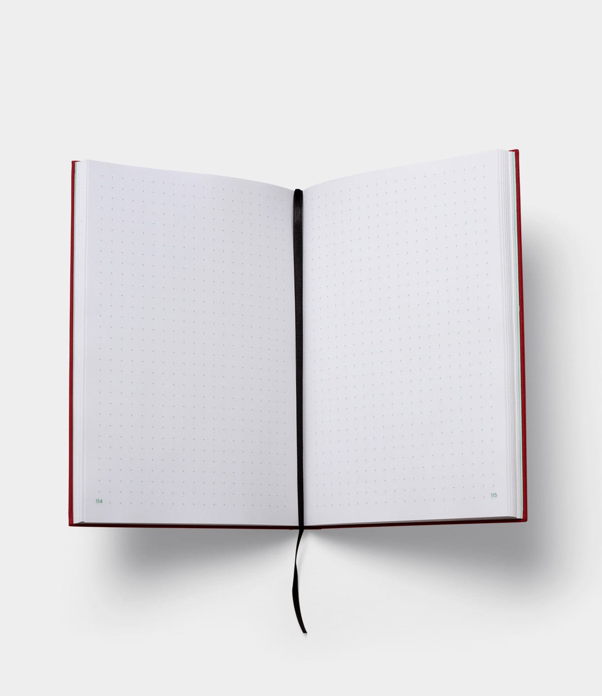 Open notebook with a red cover and dotted pages. A black ribbon bookmark is in the center of the notebook.