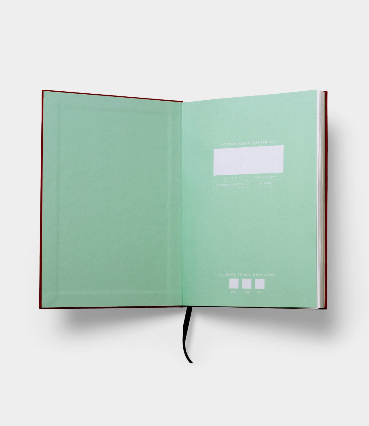 An open hardcover book with a green inside cover and a black ribbon bookmark. The left page is blank, and the right page has form fields for contact information and a label indicating ALL BOOKS THIS YEAR START with dates.