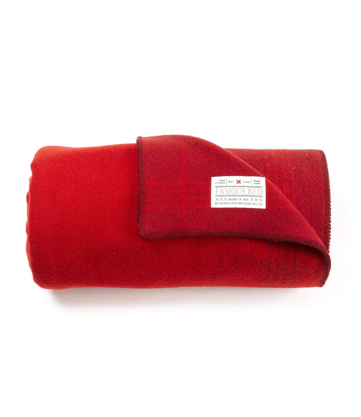 A rolled-up red wool blanket with a visible label featuring care instructions. The blanket has neatly finished edges.