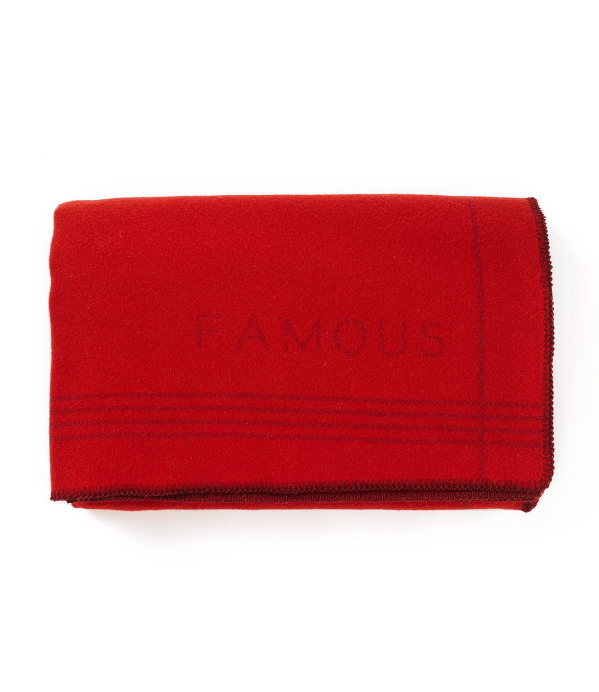 A neatly folded red blanket with the word FAMOUS embroidered on it in matching red thread.