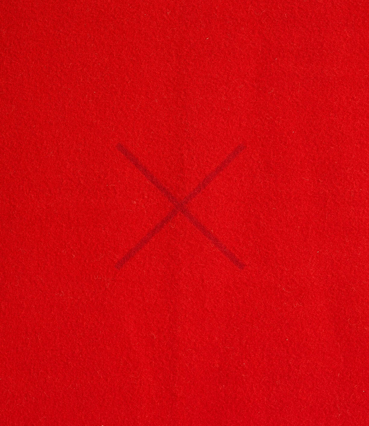 A red fabric background with a faintly visible dark red X mark in the center.