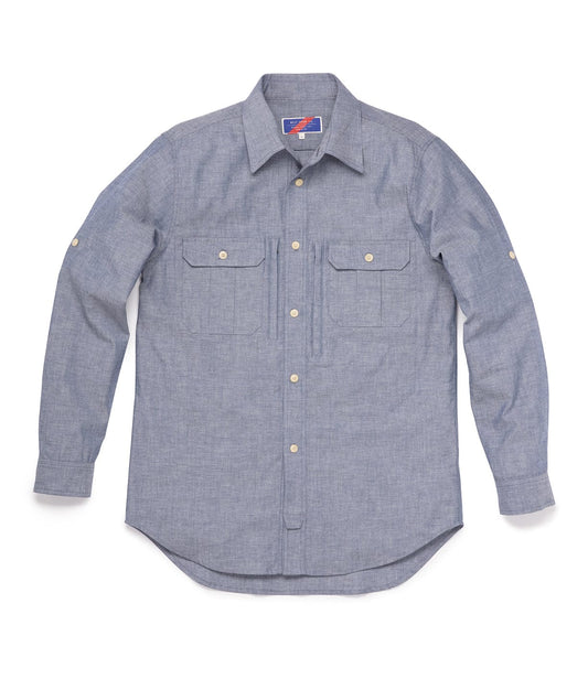 A long-sleeve button-down shirt in light blue chambray fabric, featuring two front chest pockets with button flaps.