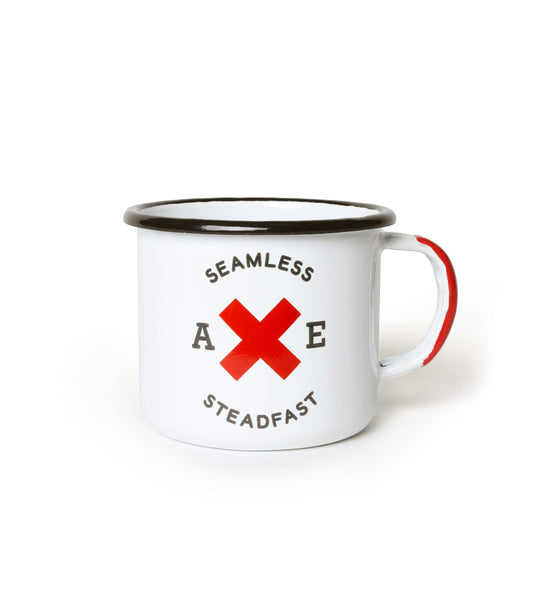 A white enamel mug with a black rim and red handle detail. It features the word SEAMLESS above, STEADFAST below, and AXE with a red X in the middle.