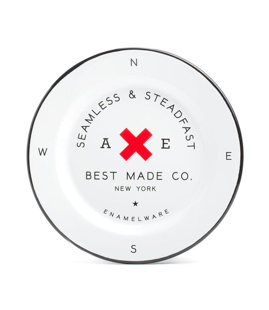 A white enamel plate from Best Made Co. with a red X in the center and compass directions (N, E, S, W) around the edge. The text reads Seamless & Steadfast above the X and Best Made Co. New York below.